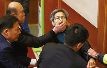 юриста Квон Ян Гука убирают из зала суда охранники, затыкая ему рот