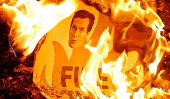 Плакат с портретом британского министра финансов Джорджа Осборна сгорает во врем
